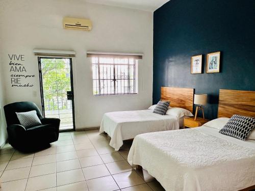 a hotel room with two beds and a chair at Espacio Libertad Colonia Americana in Guadalajara