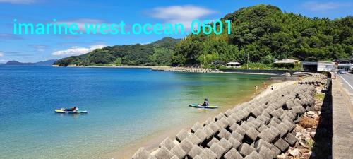 two people in boats in the water on a beach at イマジンウエストオーシャン（ImagineWestOcean） in Suo Oshima
