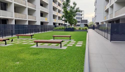 a row of benches in a park in front of a building at Modern 1BR at Ryde with Pool, Sauna & Gym in Sydney