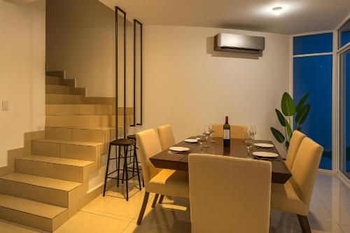 a dining room with a table and chairs and a staircase at Mansion Cumbres Vista Panoramica Monterrey in Monterrey