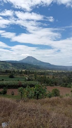 a view of a field with a mountain in the background at Bungalow Karo Hill in Berastagi