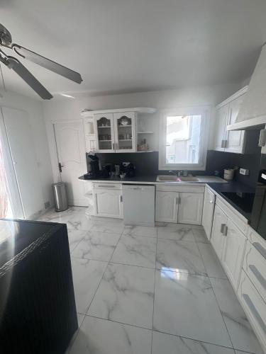 Il comprend une cuisine avec des placards blancs et un grand carrelage. dans l'établissement Maison 3chambres avec piscine, à Istres