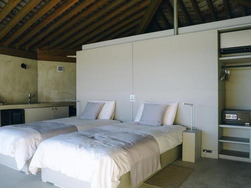 two beds sitting next to each other in a bedroom at Denpaku The Beachfront MIJORA in Amami