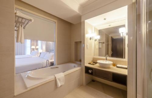 a bathroom with a bed and a tub and a sink at La Sapinette Hotel Dalat in Da Lat