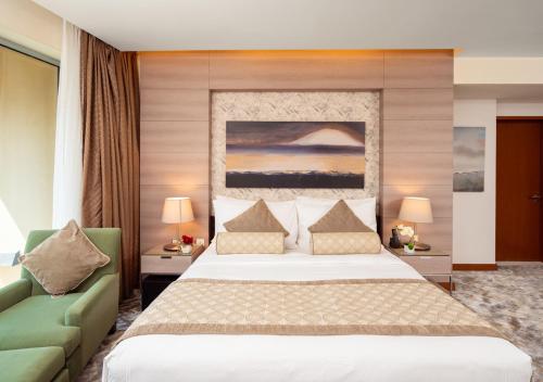 a bedroom with a large bed and a green couch at Fashion Avenue Dubai Mall in Dubai
