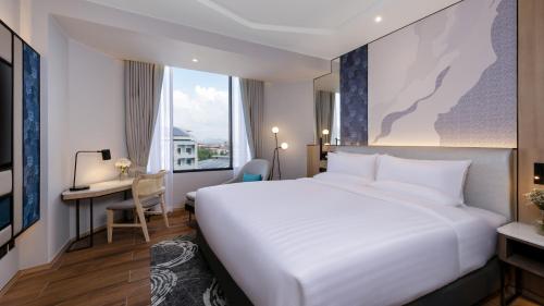a hotel room with a large bed and a desk at Novotel Rayong Star Convention Centre in Rayong