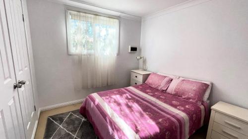 a bedroom with a pink bed and a window at On The Beach in Wooli