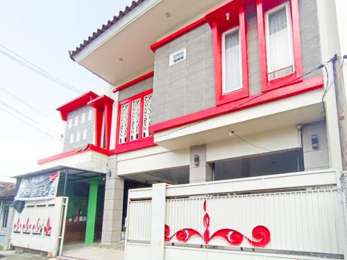 a house with red trim and a white fence at RedDoorz at Griya Jeniee Near Stadion Wilis Madiun in Madiun