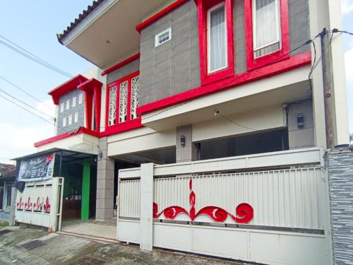 a house with a white fence in front of it at RedDoorz at Griya Jeniee Near Stadion Wilis Madiun in Madiun