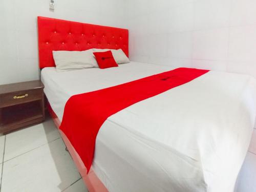 a red and white bed in a white room at RedDoorz at Griya Jeniee Near Stadion Wilis Madiun in Madiun