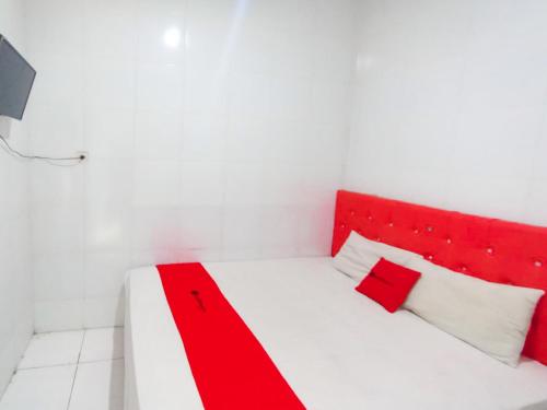 a red and white bed in a white room at RedDoorz at Griya Jeniee Near Stadion Wilis Madiun in Madiun