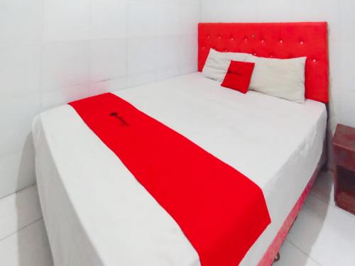 a red and white bed in a white room at RedDoorz at Griya Jeniee Near Stadion Wilis Madiun in Madiun