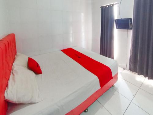 a red and white bed in a room at RedDoorz at Griya Jeniee Near Stadion Wilis Madiun in Madiun