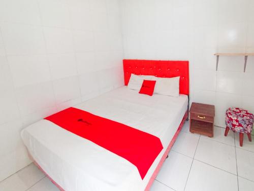 a red and white bed in a white room at RedDoorz at Griya Jeniee Near Stadion Wilis Madiun in Madiun