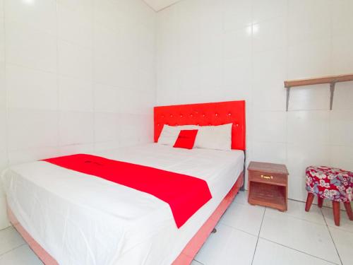 a bedroom with a large bed with a red headboard at RedDoorz at Griya Jeniee Near Stadion Wilis Madiun in Madiun