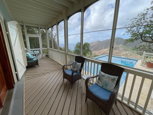 a screened in porch with two chairs and a pool at Tropical Pool Villa with Big Views and Lush Gardens in Coral Bay