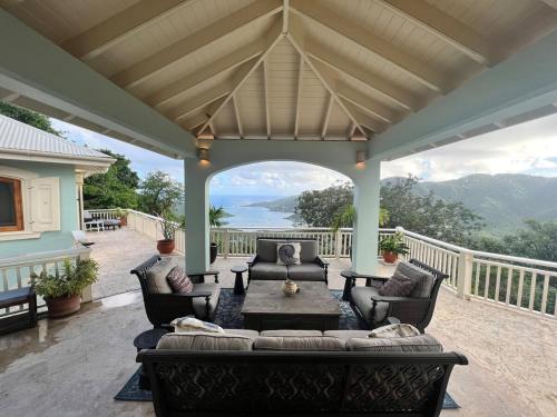 a living room with a couch and a table on a porch at Tropical Pool Villa with Big Views and Lush Gardens in Coral Bay
