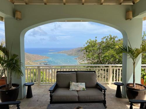 a couch on a patio with a view of the ocean at Tropical Pool Villa with Big Views and Lush Gardens in Coral Bay
