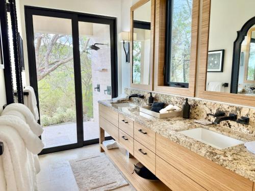 a bathroom with two sinks and a large mirror at Window to the Sea - Phenomenal Pool and Hot Tub Villa in East End