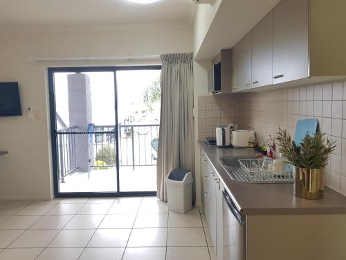 a kitchen with a counter and a sink and a window at Cairns Central Atrium Apartments & Studio in Cairns