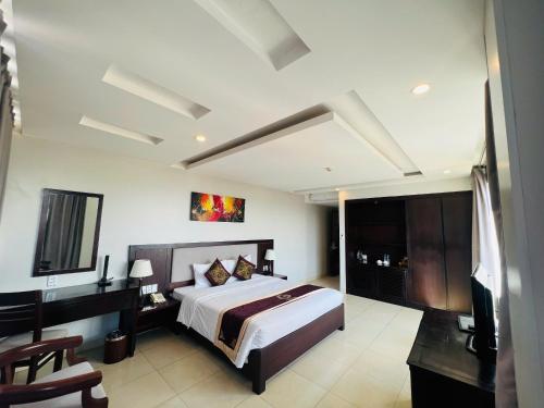 a bedroom with a bed and a desk and a television at Golden Quang Tri Hotel in Ðông Hà