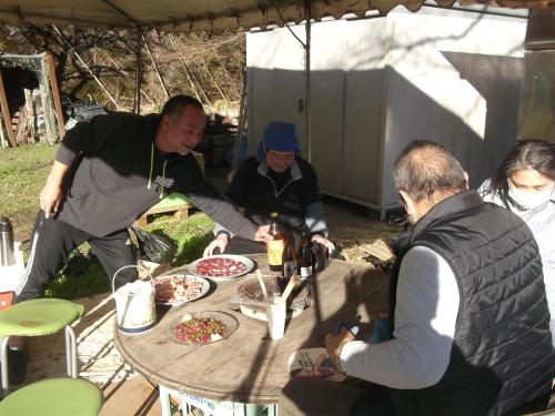 a group of people sitting around a table with food at 予約制薪割りBBQ可能! 青の洞門から車で15分 l 四季折々の自然が楽しめる農泊古民家 鍋屋 in Sugihata