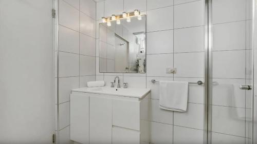 Un baño blanco con lavabo y espejo. en Seaside On Fourth, en Sawtell