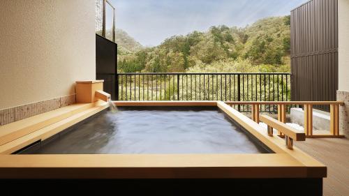 a hot tub on a balcony with a view of a mountain at Tsuganoki in Nikko