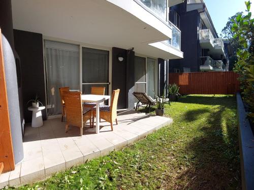 a patio with a table and chairs in a yard at Resort Pool and Garden Apartment, Nelson Bay in Nelson Bay
