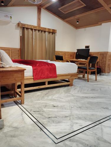 a bedroom with a bed and a desk and a piano at Hotel CM Palace - Pure Vegetarian in Ner Chowk
