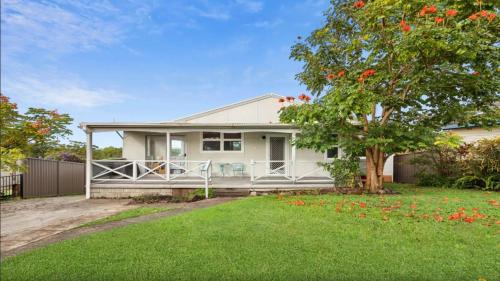 a white house with a tree in the yard at Ashcroft Cottage in Nambucca Heads