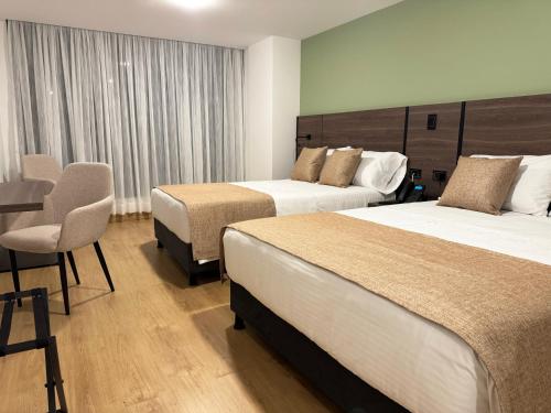 a hotel room with two beds and a chair at Entrenevados Hotel in Ipiales