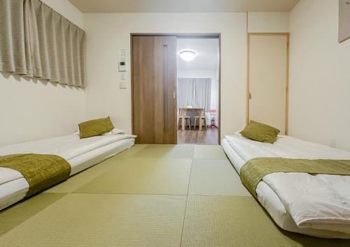 two beds in a room with white walls at HANASTAY花渓居 · 澄（KIYOSI) in Osaka