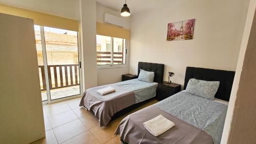 a bedroom with two beds and a balcony at SKY Way City Apartment, 150m from Chabad Lubavitch in Larnaca