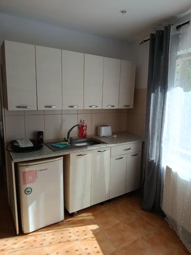 a small kitchen with white cabinets and a sink at Complex Adela Transfăgărășan in Cîrţişoara