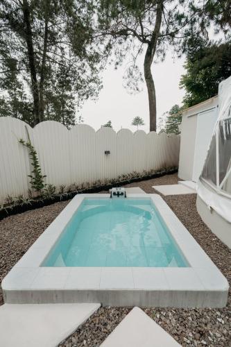 a swimming pool in a backyard with a white fence at Kaung Cabins in Cibogo