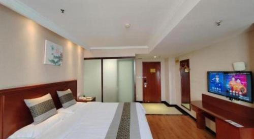 a bedroom with a large bed and a flat screen tv at GreenTree Inn Luoyang Zhongzheng Street Express Hotel in Luoyang
