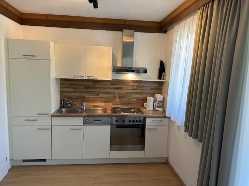 a small kitchen with white cabinets and a sink at House Egger - Top 202 in Bad Kleinkirchheim
