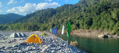 a river with a bunch of flags on the shore at REACH DESTINATION RIVERSIDE RESORT, Dawki Umngot River in Dawki