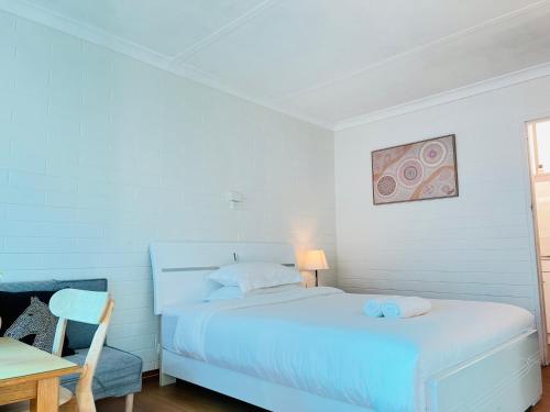 a white bedroom with a bed and a table at Motel Maroondah in Box Hill