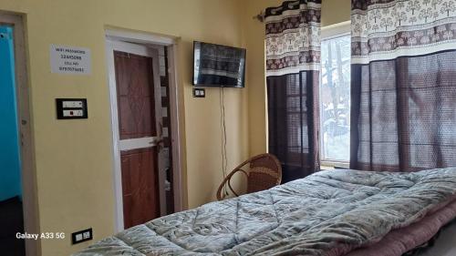 a bedroom with a bed and a window with a television at Al-Ayaan Guest House in Pahalgām