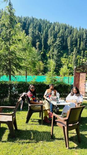 a group of people sitting at a table in the grass at Al-Ayaan Guest House in Pahalgām