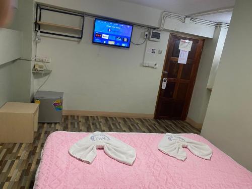 a room with a bed with pink sheets and a tv at Miracle Gallery Hotel in Makkasan