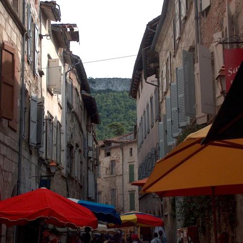 an alley with tables and umbrellas in a city at L'Atelier, Confort, Bain à remous et Nature in Parisot-Tarn-et-Garonne