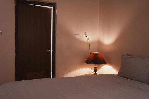 a bedroom with a bed with a lamp and a door at 牧嶼 Nomads' Isle in Jinhu