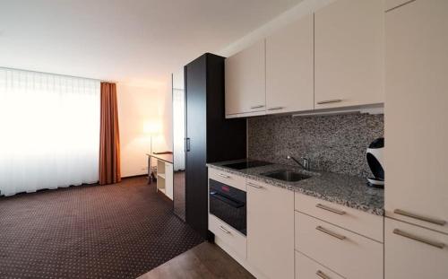 a kitchen with white cabinets and a sink and a window at Motel Fehraltorf in Fehraltorf