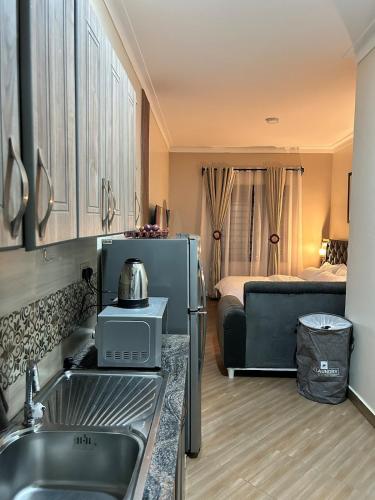 a kitchen with a sink and a refrigerator and a bed at Studio room in Kira, Bulindo in Bulindo
