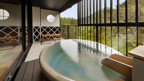 a bath tub in the middle of a room with a balcony at Tsuganoki in Nikko