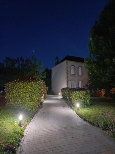 a pathway leading to a building at night with lights at Chic & charme au Presbytère in Saint-Genès-du-Retz