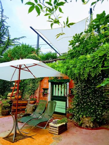 a patio with an umbrella and two chairs and a table at Krasberry Ježev brlog in Komen